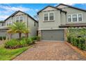 Charming townhome featuring a two-car garage, brick paver driveway, and lovely landscaping with a palm tree at 5086 San Martino Dr, Wesley Chapel, FL 33543