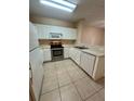 Efficient kitchen featuring stainless steel appliances, white cabinets, and tile flooring at 6002 Osprey Lake Cir, Riverview, FL 33578