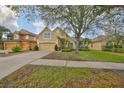 Traditional tan home with an attached two-car garage and mature landscaping in a suburban neighborhood at 7708 Nottinghill Sky Dr, Apollo Beach, FL 33572