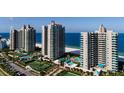 Aerial view of beachfront condos, revealing amenities like pools and tennis courts amid lush landscaping at 1520 Gulf Blvd # Ph2, Clearwater Beach, FL 33767
