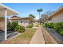 Landscaped condo exterior featuring green shrubs, pavers, and a walkway to the front door at 2260 Oak Neck Rd # B, Clearwater, FL 33763