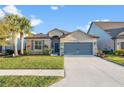 Inviting front exterior featuring a well-maintained lawn, mature palm trees, and a gray two-car garage at 5406 Levana St, Palmetto, FL 34221