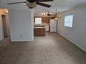 Open-concept living space with neutral carpeting, ceiling fans, and access to a fully-equipped kitchen at 6704 Hickorywood Ln # 2B, New Port Richey, FL 34653