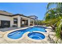 Backyard with a lagoon-style pool and spa, a covered patio, lounge chairs, and lush tropical landscaping at 8307 Bluevine Sky Dr, Land O Lakes, FL 34637