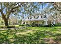 Charming exterior featuring a metal roof, dormer windows, and rocking chairs on the porch at 10101 Tarpon Springs Rd, Odessa, FL 33556