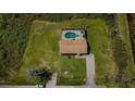 Aerial view of a home with an enclosed pool surrounded by greenery and a well-kept lawn at 10603 1St St, Riverview, FL 33569