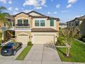 Two-story tan home with a well-maintained lawn, two car garage, and lush landscaping at 11641 Crowned Sparrow Ln, Tampa, FL 33626