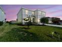 Exterior view of a well-maintained two-story home with a green lawn and landscaped surroundings at dusk at 10741 Charlotte Dr, Parrish, FL 34219