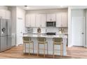 Stylish kitchen with white cabinets, stainless steel appliances, island with breakfast bar, and wood floors at 12160 Cattleside Dr, Riverview, FL 33579