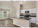 Modern kitchen with stainless steel appliances, dark countertops, white cabinets, and an island with a sink at 14777 Summer Branch Dr, Lithia, FL 33547