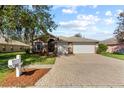 Charming single-story home with brick driveway, mature trees, and a three-car garage at 19826 Wyndham Lakes Dr, Odessa, FL 33556