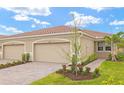 Single-story house featuring a two-car attached garage, tile roof, well-manicured lawn, and paved walkway at 20387 Symphony Pl, Venice, FL 34293