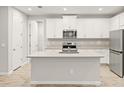 Bright kitchen boasts white cabinets, stainless steel appliances and center island at 20387 Symphony Pl, Venice, FL 34293