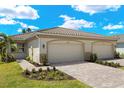 Charming single-story home featuring a two-car garage, tile roof, and lush landscaping creating curb appeal at 20405 Symphony Pl, Venice, FL 34293