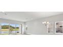 Bright living room with sliding glass doors, large windows overlooking scenic view, and elegant chandelier at 35593 Stableton Ln, Zephyrhills, FL 33541