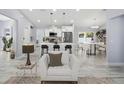 Open living space with white kitchen, island with seating, and a comfortable armchair on stylish flooring at 104 1St Ne Ave, Lutz, FL 33549