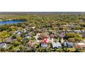 Aerial view of a neighborhood with tree lined streets, lake and home with screened in pool at 15703 Jericho Dr, Odessa, FL 33556