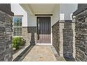 An up-close view of the beautiful front door with stone columns, a paved walkway and landscaped features at 16946 Oval Rum Dr., Wimauma, FL 33598
