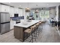 Modern kitchen featuring white cabinets, stainless steel appliances, large island with seating and hardwood flooring at 17420 Moonflower Dr # 102, Venice, FL 34293
