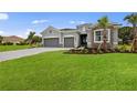 Inviting single-story home with a lush green lawn, gray driveway, and stone facade details at 24041 Peppercorn Rd, Punta Gorda, FL 33955