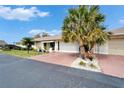 Charming single-story home with a red driveway and lovely landscaping, complemented by mature palm trees under a clear sky at 312 Fairside Ct # 12, Sun City Center, FL 33573