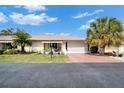 Quaint single-story home with a red driveway, manicured lawn, and mature palm trees on a sunny day at 312 Fairside Ct # 12, Sun City Center, FL 33573