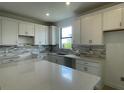 Modern kitchen featuring white cabinets, quartz countertops, and stylish backsplash at 5014 Coastal Oak Ct, Lakewood Ranch, FL 34211