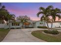 Charming single-story home at twilight, featuring lush landscaping and a circular driveway at 1003 39Th Ne Ave, St Petersburg, FL 33703