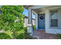 Inviting front entrance showcases a blue door adorned with a wreath, complemented by stylish columns and verdant landscaping at 19437 Ship Wheel Way, Land O Lakes, FL 34638