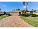Inviting home featuring a lush lawn, colorful landscaping, and a brick driveway at 2222 Mayfield Palms Ln # 322, Sun City Center, FL 33573
