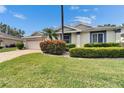 Home with vibrant green lawn, colorful bushes, brick driveway, and charming architectural details at 2222 Mayfield Palms Ln # 322, Sun City Center, FL 33573