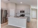Bright kitchen with stainless steel appliances, island, and light gray cabinetry at 37233 Sagemoor Dr, Zephyrhills, FL 33541