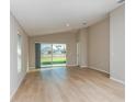 Bright living room featuring wood flooring, neutral walls, and sliding glass door to the backyard at 37233 Sagemoor Dr, Zephyrhills, FL 33541