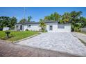 Newly paved driveway leading to a charming white home with dark trim and well-manicured lawn at 1102 N Albany Ave, Tampa, FL 33607