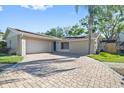 Charming home featuring a two-car garage, a blue front door, and a beautifully paved driveway at 12605 Catamaran Pl, Tampa, FL 33618