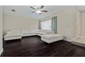 Bright living room featuring dark hardwood floors, a ceiling fan, and a stylish, white sectional sofa at 12605 Catamaran Pl, Tampa, FL 33618