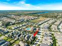 Expansive aerial view showcasing the neighborhood with community pool, surrounding trees, and a glimpse of a nearby lake at 6002 Thrushwood Rd, Lithia, FL 33547