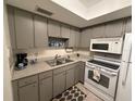 Functional kitchen features grey cabinets, white appliances, and ample counter space at 865 Virginia Ct # 106, Dunedin, FL 34698