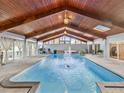 Indoor pool featuring a fountain, wood ceiling, and natural light streaming through windows for year-round enjoyment at 8693 15Th N St, St Petersburg, FL 33702