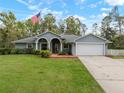 Charming single-story home featuring a well-manicured lawn and an inviting arched entryway with American flag at 1126 Oxbow Rd, Wimauma, FL 33598