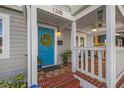 Welcoming front porch with a bright blue door, brick steps, and cozy seating area at 1205 13Th N St, St Petersburg, FL 33705