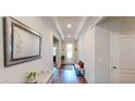Bright entryway with tray ceiling, hardwood floors, and a decorative mirror at 12403 Brick Cobblestone Dr, Riverview, FL 33579