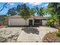 Inviting single-story home featuring a two-car garage, well-kept landscaping, and a welcoming screened porch at 1368 Noell Blvd, Palm Harbor, FL 34683