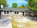 Inviting single-story home with stone accents, neat landscaping, and a cozy front patio seating area at 26419 Rolling Acres E Dr, Brooksville, FL 34602