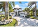 Beautiful two-story white home with a brick driveway, lush tropical landscaping and palm trees at 3006 Christophers Watch Ln, Ruskin, FL 33570