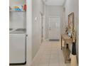 Bright hallway featuring tile flooring, access to the laundry area, and a decorative table next to the front door at 3412 Trapnell Ridge Dr, Plant City, FL 33567