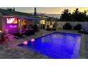 Night view of an outdoor pool with neon sign, poolside lounge area, and flamingo pool floats at 427 79Th Ave, St Pete Beach, FL 33706