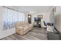 Cozy living room featuring modern laminate flooring, a plush sofa, and large windows at 7143 Sealawn Dr, Spring Hill, FL 34606