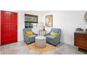 Inviting sitting area featuring stylish armchairs, a round ottoman, a side table, and a brightly colored red door at 1110 S Pine Lake Dr, Tampa, FL 33612