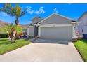 Inviting one-story home with a two-car garage, well-kept lawn, and lush landscaping at 15414 Fire Rock Pl, Ruskin, FL 33573